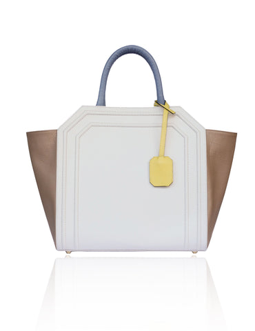 Structured cream and sand textured leather Sharon tote with teal blue handles, banana yellow tag, and gold-tone hardware.