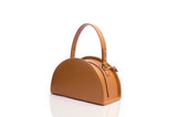 Tan grainy leather taco-shaped handbag with a curved top handle and gold-tone hardware on a white background.